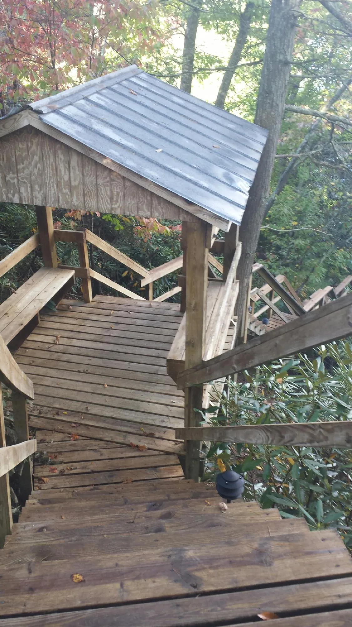 Metal roofed shelter over wooden steps on a wooded walkway — Skylight Repair & Installation work by our crew in Tiffin
