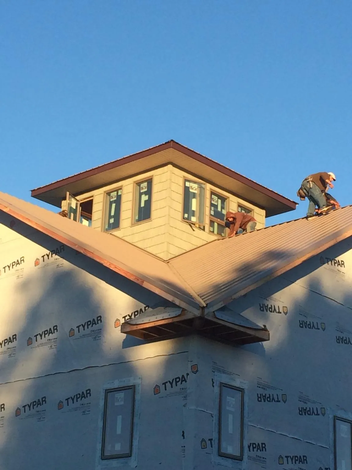 Roofers working around a rooftop cupola on a new metal roof at sunset — Roof Waterproofing in Tiffin by Roofing Brothers